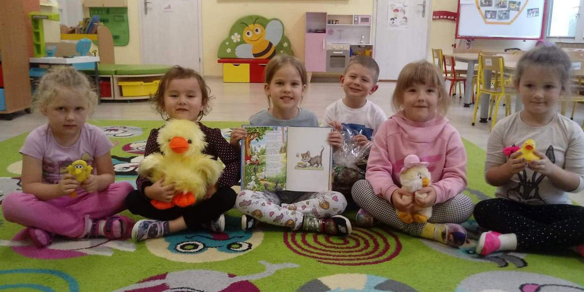 dzieci z otwartą książka siedzą na dywanie