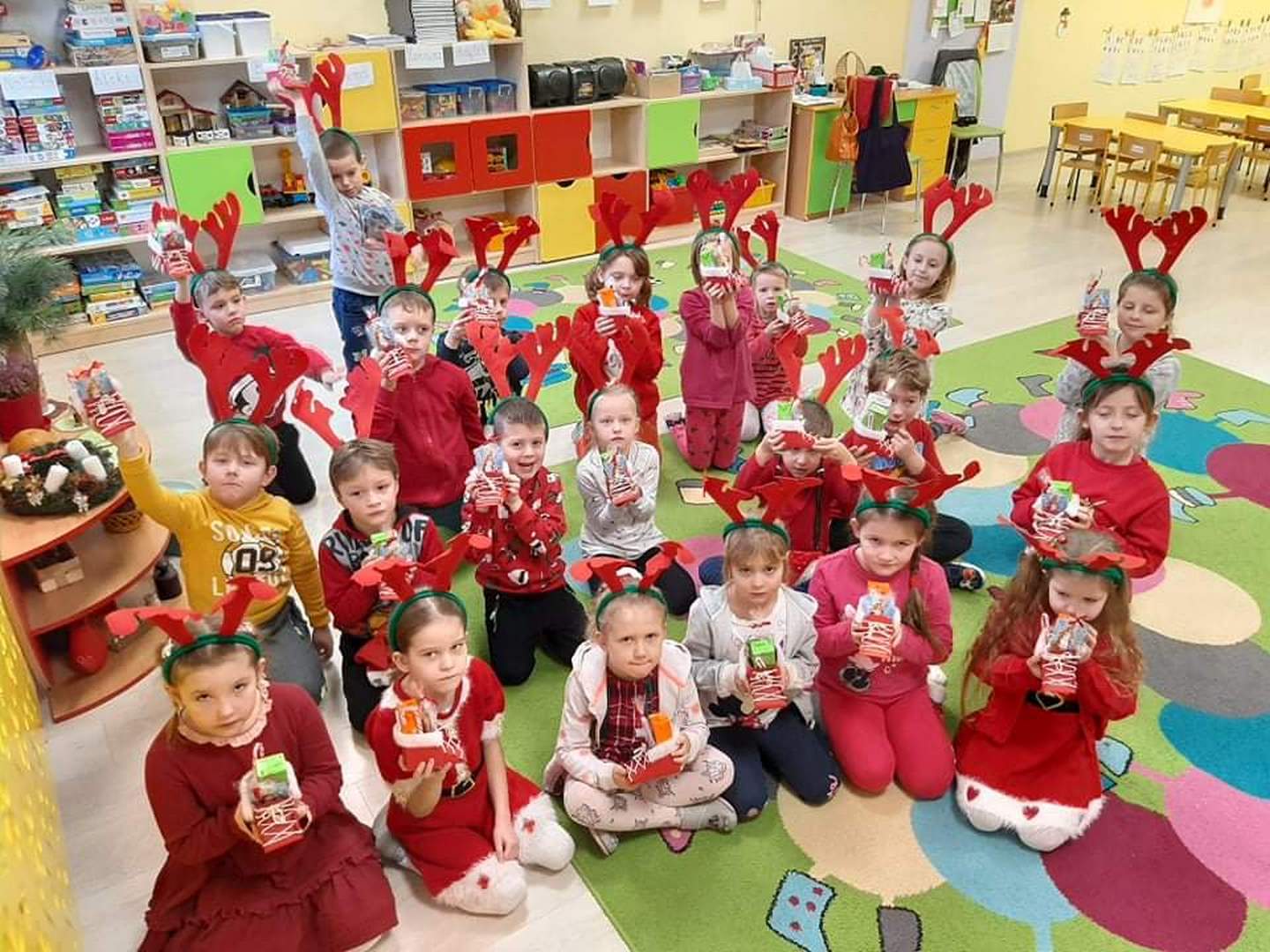 grupa dzieci ubrana na czerwono prezentuje buciki od Św. Mikołaja