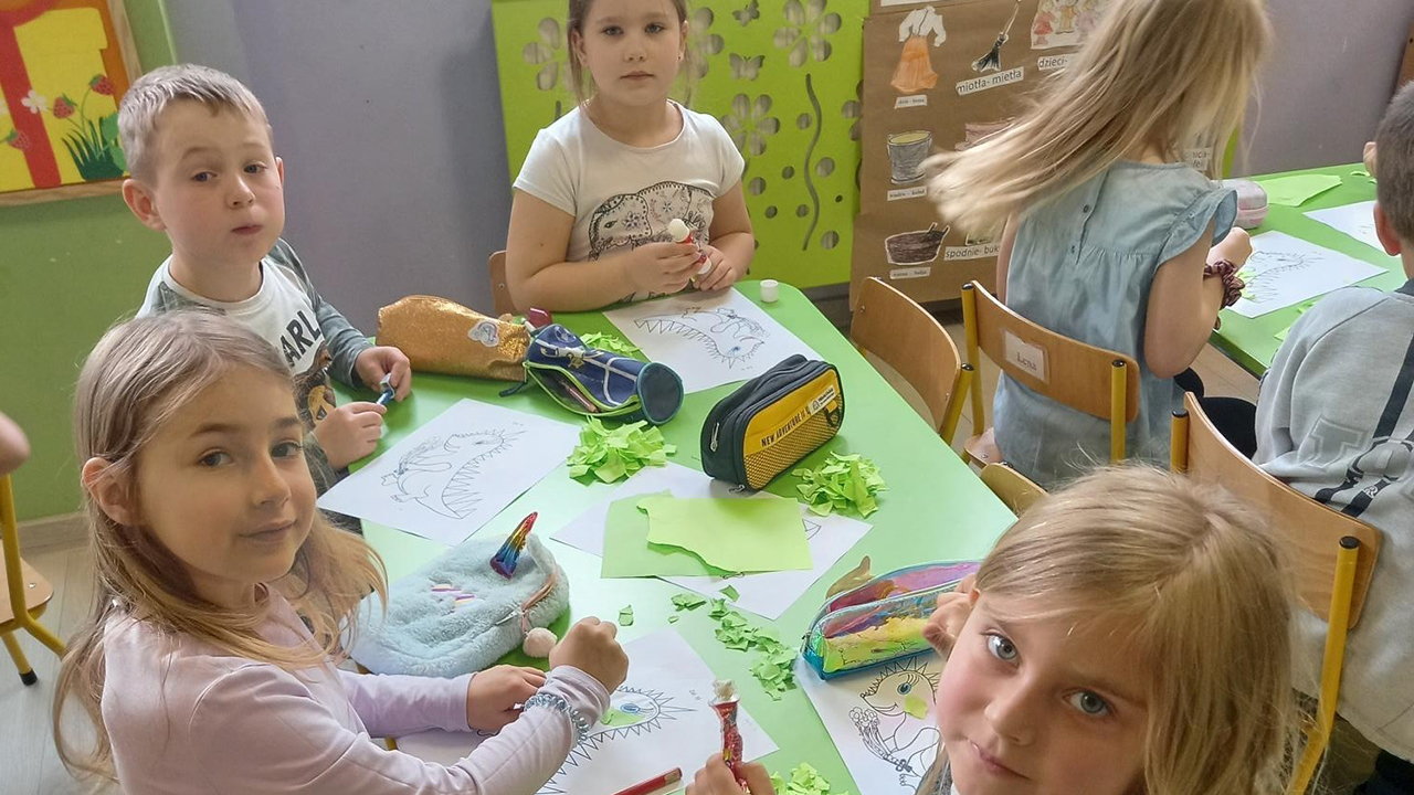 dzieci przy stoliku tworzą prace plastyczną