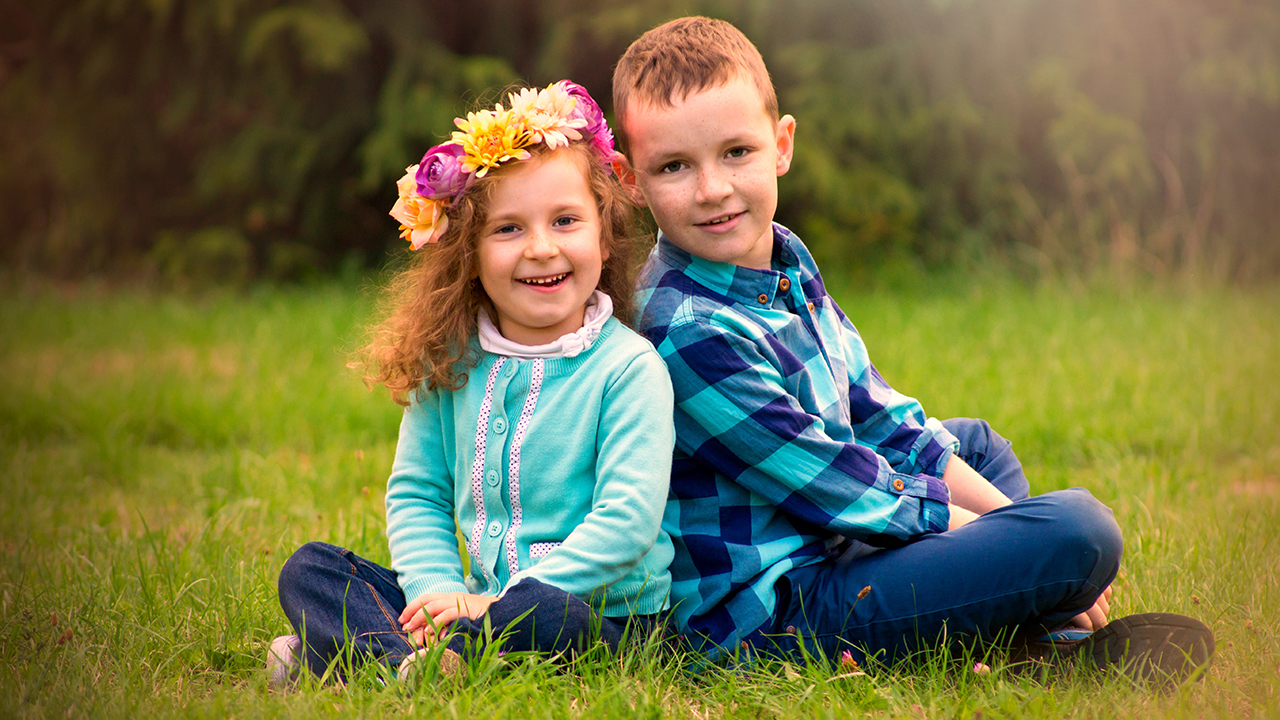 dziewczynka i chłopiec siedzą na trawie