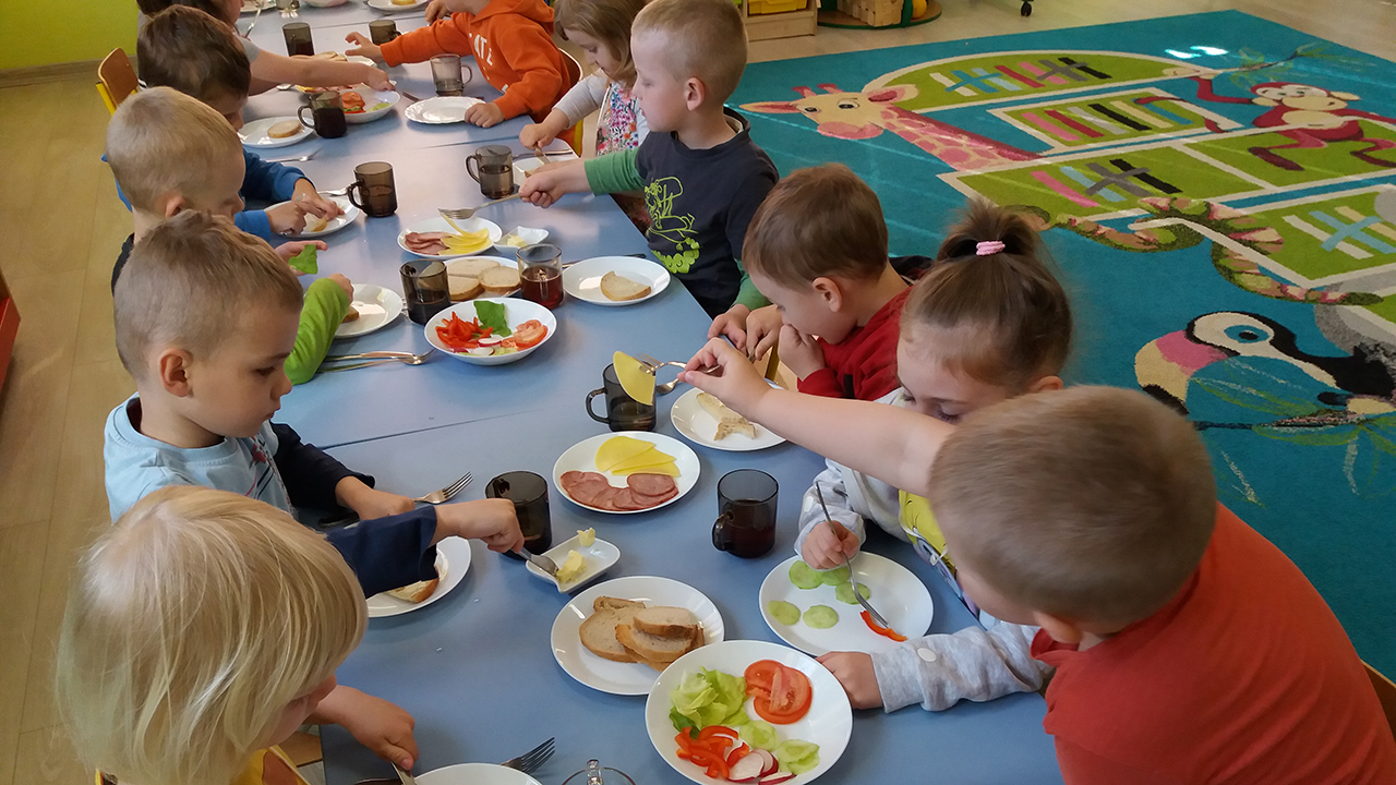 dzieci jedzą posiłek przy stole