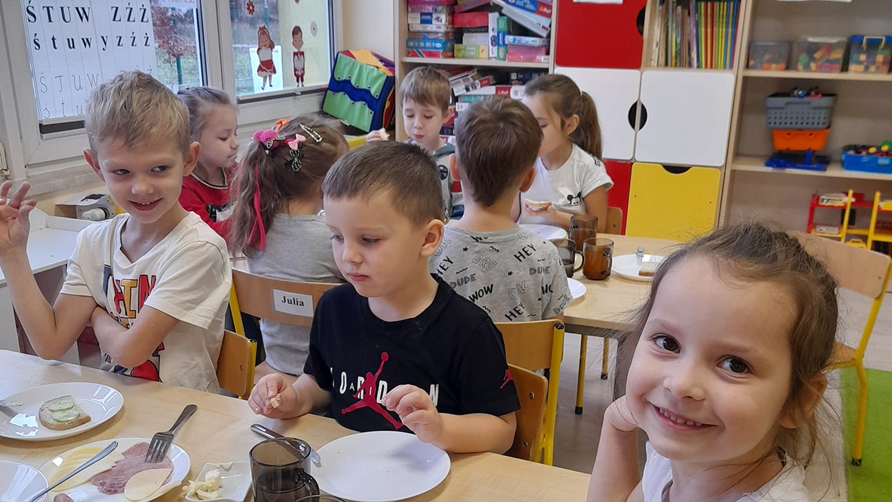 Dzieci jedzą śniadanie przy stoliczku