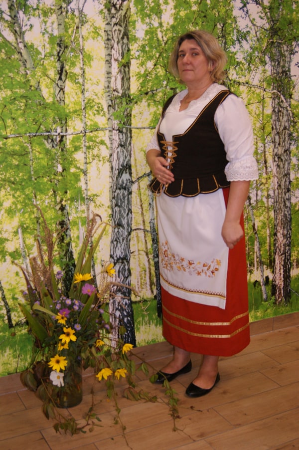 Beata Mańkowska w stroju borowiackim na tle brzóz