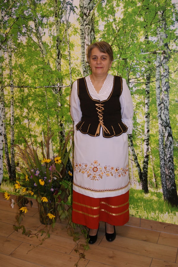 Elżbieta Skwiercz  w stroju borowiackim na tle brzóz