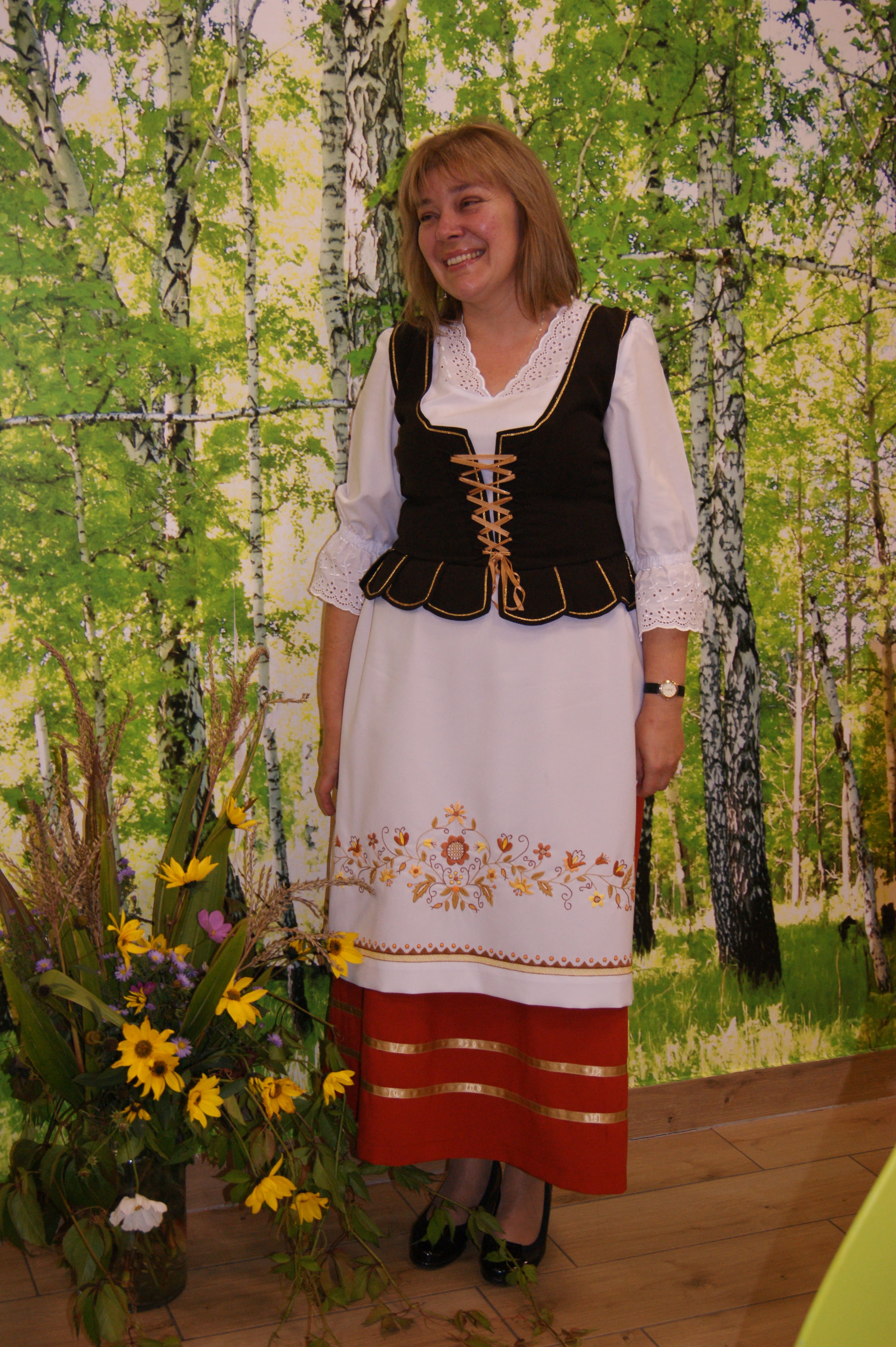 Jolanta Wiczanowska   w stroju borowiackim na tle brzóz