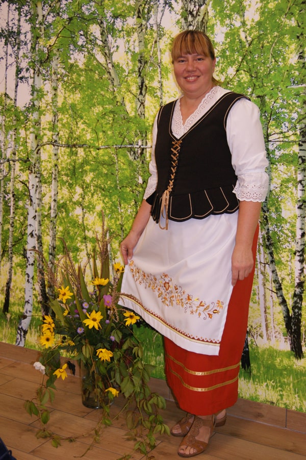 Katarzyna Muszyńska  w stroju borowiackim na tle brzóz